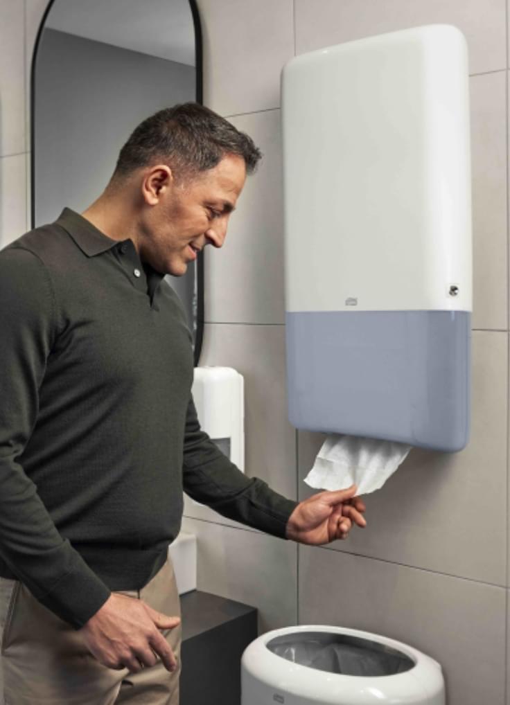 Mężczyzna korzystający z dozownika Tork w łazience