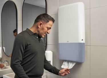 Mężczyzna korzystający z dozownika Tork w łazience